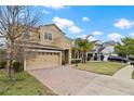 Charming house with brick driveway, 2-car garage, manicured lawn, and palm trees providing shade at 2371 Victoria Dr, Davenport, FL 33837