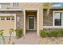 Inviting entryway featuring a stone facade, dark green front door, and well-manicured shrubbery at 2371 Victoria Dr, Davenport, FL 33837