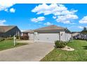 Single-story home with a two-car garage, well-kept lawn, and charming curb appeal at 381 Corbett Dr, The Villages, FL 32162