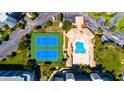 Overhead shot of a community pool, clubhouse, and tennis courts in a tropical setting, surrounded by green lawns at 5300 S Atlantic Ave # 7-301, New Smyrna Beach, FL 32169