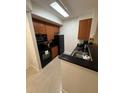 A compact kitchen featuring dark countertops, dark wooden cabinets, and a suite of black appliances at 7395 Universal Blvd # 104, Orlando, FL 32819