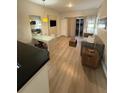 Well-lit living area with a sofa, modern table, and mounted TV, complemented by light wood flooring at 7395 Universal Blvd # 104, Orlando, FL 32819