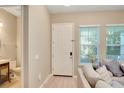 Bright foyer with light wood floors, complemented by a adjacent bathroom and modern gray sofa near the window at 8321 Bryce Canyon Ave, Windermere, FL 34786