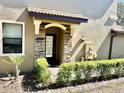 Stylish front entryway featuring stone accents, a covered porch, and verdant landscaping at 8923 Azalea Sands Ln, Davenport, FL 33896