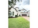 Inviting two-story home with a cylindrical tower, dark garage door, and lush green lawn at 9207 Busaco Park Way, Winter Garden, FL 34787