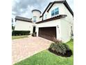Charming two-story house with a cylindrical tower, brick driveway, and well-maintained yard at 9207 Busaco Park Way, Winter Garden, FL 34787