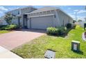 Single-story home featuring a two-car garage and brick driveway on a sunny day at 1009 Hendon Loop, Davenport, FL 33837