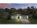 Twilight shot of single Gathering home, manicured lawn, neutral paint and gray garage door at 1377 Tappie Toorie Cir, Lake Mary, FL 32746