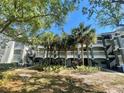 View of condo complex featuring balconies, stairs, palm trees and lush landscaping on a sunny day at 13827 Fairway Island Dr # 1232, Orlando, FL 32837