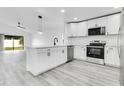 Modern kitchen features stainless steel appliances, white cabinets, an island with seating, and stylish light fixtures at 150 Chicago Woods Cir, Orlando, FL 32824