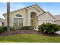 Front exterior of home featuring an arched entry, manicured landscaping, and an attached two-car garage at 155 Barefoot Beach Way, Kissimmee, FL 34746