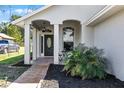 Inviting front porch with a decorative front door, a small bistro table, and lush landscaping at 1613 N Lakewood Ave, Ocoee, FL 34761