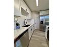 Galley kitchen features white cabinets, stainless steel appliances, and gray wood-look flooring at 1920 E Edgewood Dr # A5, Lakeland, FL 33803