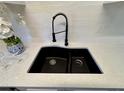 Close-up of a modern, deep kitchen sink with a sleek black faucet and white quartz countertops at 1920 E Edgewood Dr # A9, Lakeland, FL 33803