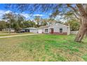 Cozy home with a lush front yard, long driveway, and inviting red door framed by mature trees at 3357 Shalimar Cir, Deltona, FL 32738