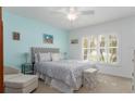 Cozy bedroom featuring a tufted headboard, calming blue accent wall, and natural light from shuttered windows at 5025 St Andrews Arc, Leesburg, FL 34748