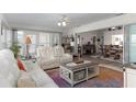 A sunlit living room features white leather seating and stylish decor, adjacent to the dining area at 5025 St Andrews Arc, Leesburg, FL 34748
