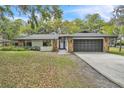 Charming single-story home with stone accents, a dark gray garage door, and manicured lawn at 5374 Crooked Oak Cir, St Cloud, FL 34771