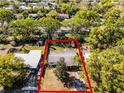 Aerial view of a home with a mature tree in the front yard, surrounded by lush greenery and a red outlined boundary at 818 Logan Dr, Longwood, FL 32750