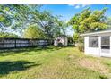 View of the backyard with green grass, wooden fence, shed, and mature tree at 818 Logan Dr, Longwood, FL 32750