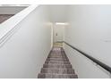 View of a clean staircase with white walls and a dark handrail leading up to a bright white door at 9093 Lee Vista Blvd # 905, Orlando, FL 32829