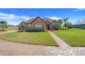 Beautifully landscaped home with a brick driveway and a well-manicured lawn at 10544 Spring Lake Dr, Clermont, FL 34711