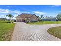 Charming home featuring a three-car garage, brick driveway and lush landscaping at 10544 Spring Lake Dr, Clermont, FL 34711