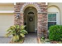 Charming front entrance with stone archway, a decorative wreath, and lush landscaping at 10942 High Bush Ct, Orlando, FL 32825
