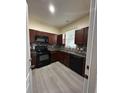 Efficient kitchen featuring dark wood cabinetry, black appliances, and modern backsplash at 178 Chippendale Ter, Oviedo, FL 32765