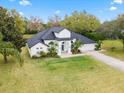 Landscaped yard and white home with a dark roof and a paver walkway at 30912 Fairvista Dr, Tavares, FL 32778