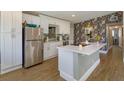 Modern kitchen with white cabinets, stainless steel refrigerator, kitchen island, and stylish floral wallpaper at 427 Zimmerman Dr, Orlando, FL 32839