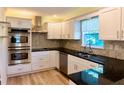 Modern kitchen with stainless steel appliances, black countertops, and white cabinets at 5108 Sunrise Blvd, Orlando, FL 32803