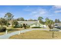 Charming single-story home with well-manicured lawn, mature trees, and a long driveway leading to the attached garage at 5170 Ne 64Th Ave, Silver Springs, FL 34488