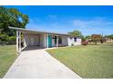 Charming home featuring a well-maintained lawn, a covered carport, and a vibrant turquoise front door at 544 Eartha Ln, Orlando, FL 32805