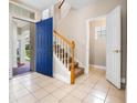 Bright foyer featuring tile floors, a wooden staircase, and a vibrant blue front door at 8426 Foxworth Cir # 44, Orlando, FL 32819