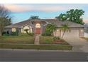 Dusk view of a single-story home with mature landscaping and a two-car garage at 907 Almond Tree Cir, Orlando, FL 32835