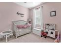 Bedroom featuring pink walls, a crib, a play kitchen, and natural light from the window at 1452 Hopedale Pl, Sanford, FL 32771