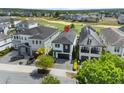 Aerial view of a modern residence overlooking a golf course, featuring a dark roof, and manicured landscaping at 1543 Corolla Ct, Reunion, FL 34747