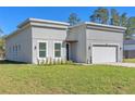 Contemporary home exterior with gray stucco, two-car garage and manicured front yard at 17135 Sw 41 Ct, Ocala, FL 34473