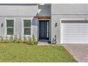 Modern home exterior featuring a black front door, manicured lawn, and a brick paver walkway at 17135 Sw 41 Ct, Ocala, FL 34473