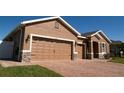 Exterior home view featuring a 3 car garage with brick paved driveway and updated lighting fixtures at 1855 Partin Terrace Rd, Kissimmee, FL 34744
