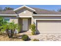 Inviting home exterior with a paver driveway, a two-car garage, and lush landscaping at 188 Whispering Pines Way, Davenport, FL 33837
