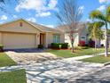 Well-maintained single-story home with a brick driveway and manicured landscaping on a sunny day at 734 Andalusia Loop, Davenport, FL 33837