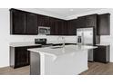 Modern kitchen featuring dark cabinets, stainless steel appliances, and a bright white island with a sink at 1209 Mattie Pointe Blvd, Auburndale, FL 33823