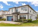 Charming two-story home with a blue garage door, modern windows and manicured landscaping at 1242 Butterfly Orchid Rd, Davenport, FL 33837