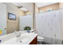 Bathroom featuring a large mirror, white sink, toilet, and shower with a floral-patterned curtain at 1720 Bridgets Ct, Kissimmee, FL 34744