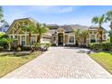 View of the home's front exterior, brick driveway, attached garage, and manicured tropical landscaping at 1720 Bridgets Ct, Kissimmee, FL 34744