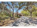 Wide shot of a property with a terracotta tile roof, mature trees, and a long gravel driveway at 275 Clearview Rd, Chuluota, FL 32766