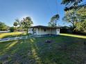 Cozy one-story home with a covered carport, surrounded by lush greenery under a clear blue sky at 5115 W Livingston St, Orlando, FL 32811