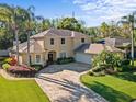 Two-story home boasting a brick paver driveway, mature trees, manicured landscaping, and a side-entry garage at 5325 Cypress Reserve Pl, Winter Park, FL 32792